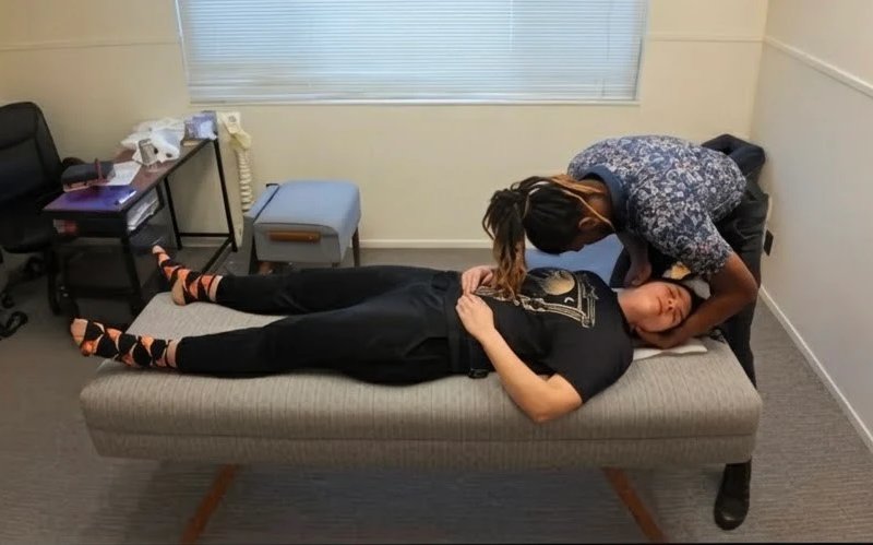 Dr. Kendell Jack performing a neck adjustment on a patient lying on their back