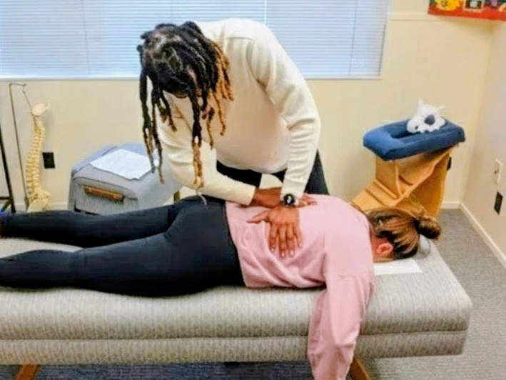 Dr. Kendell Jack performing a back adjustment on a patient lying face-down